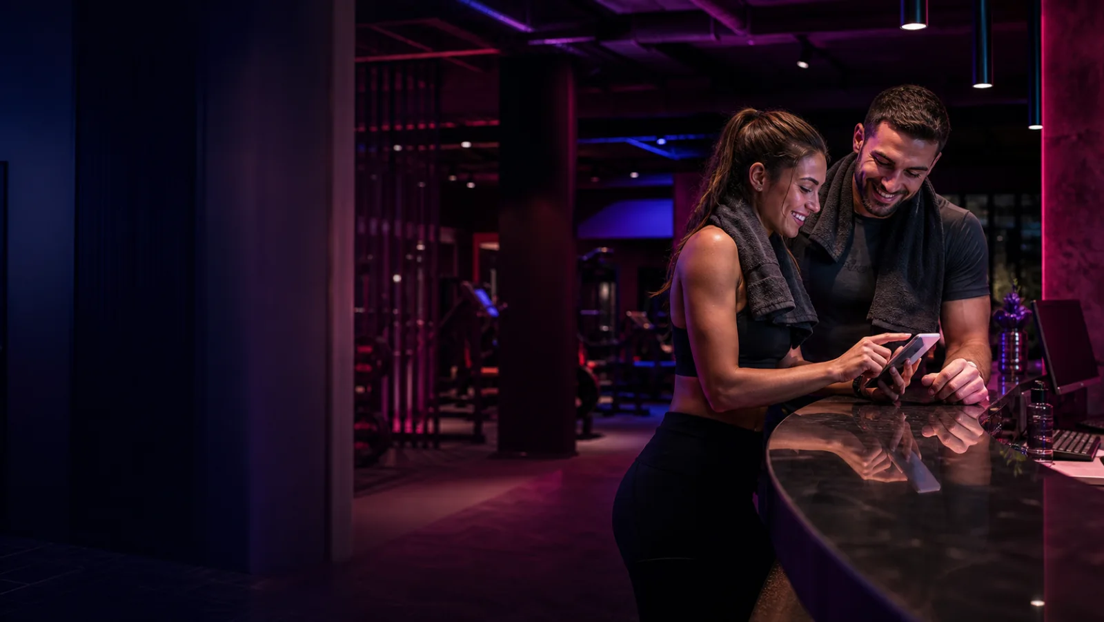 Two gym members using a phone at reception